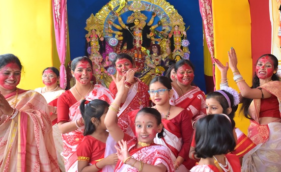 Married women joyfully play Sindur Khela, smearing vermillion, while children dance during Agartala