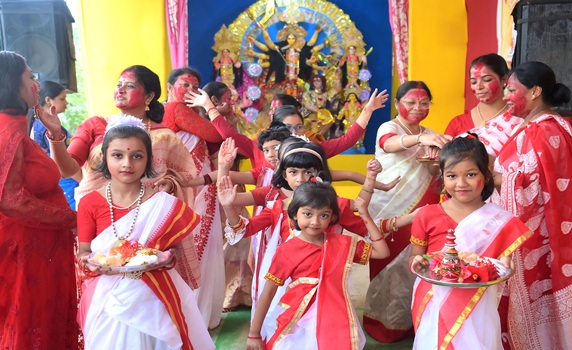 Married women joyfully play Sindur Khela, smearing vermillion, while children dance during Agartala