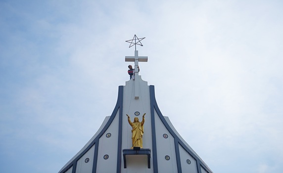 A worker cleans a cross on the top of Don Bosco Church ahead of Christmas at Agartala. PIC- Abhisek